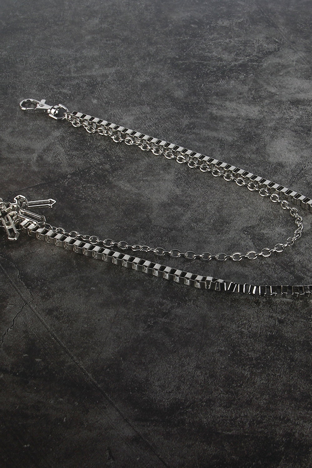 Silver geometric chain waist accessory with crossed charms and lobster clasp.