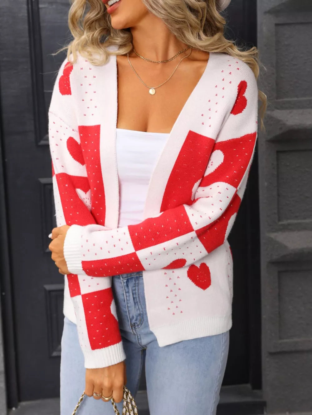 White and red heart motif knit cardigan with checkered sleeves and open front.
