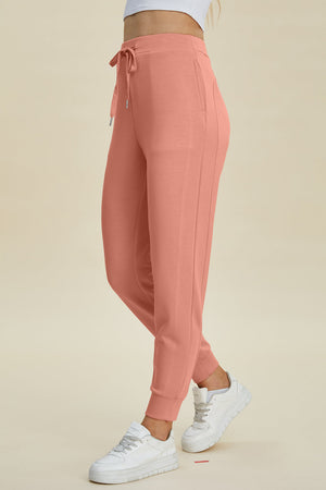 Coral joggers with drawstring waist and cuffed ankles, styled with white sneakers.