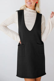 Black knit sweater dress with deep V-neck and two front pockets, layered over a cream ribbed turtleneck.