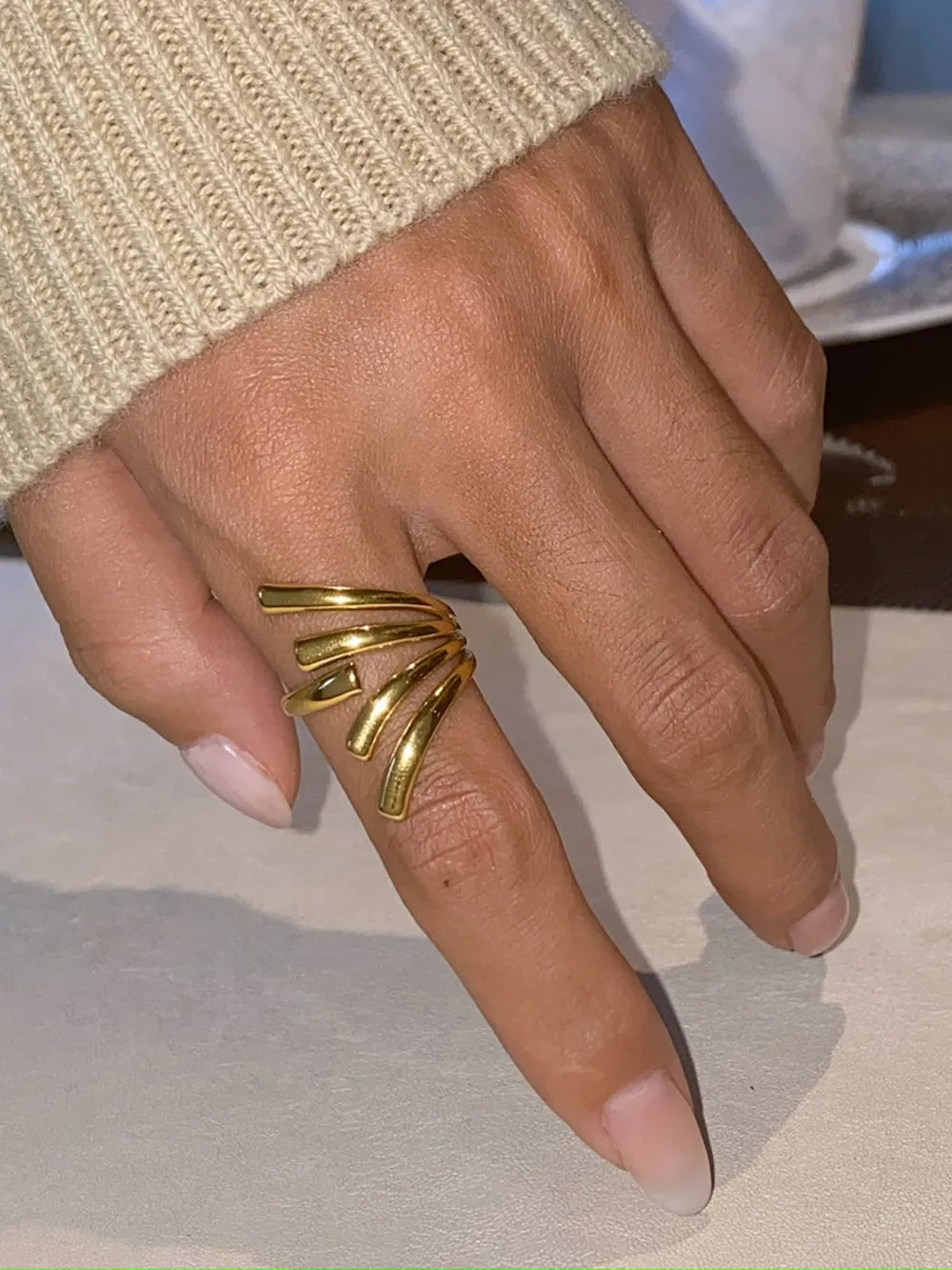 Gold sculptural spiral ring with multiple bands on a finger.