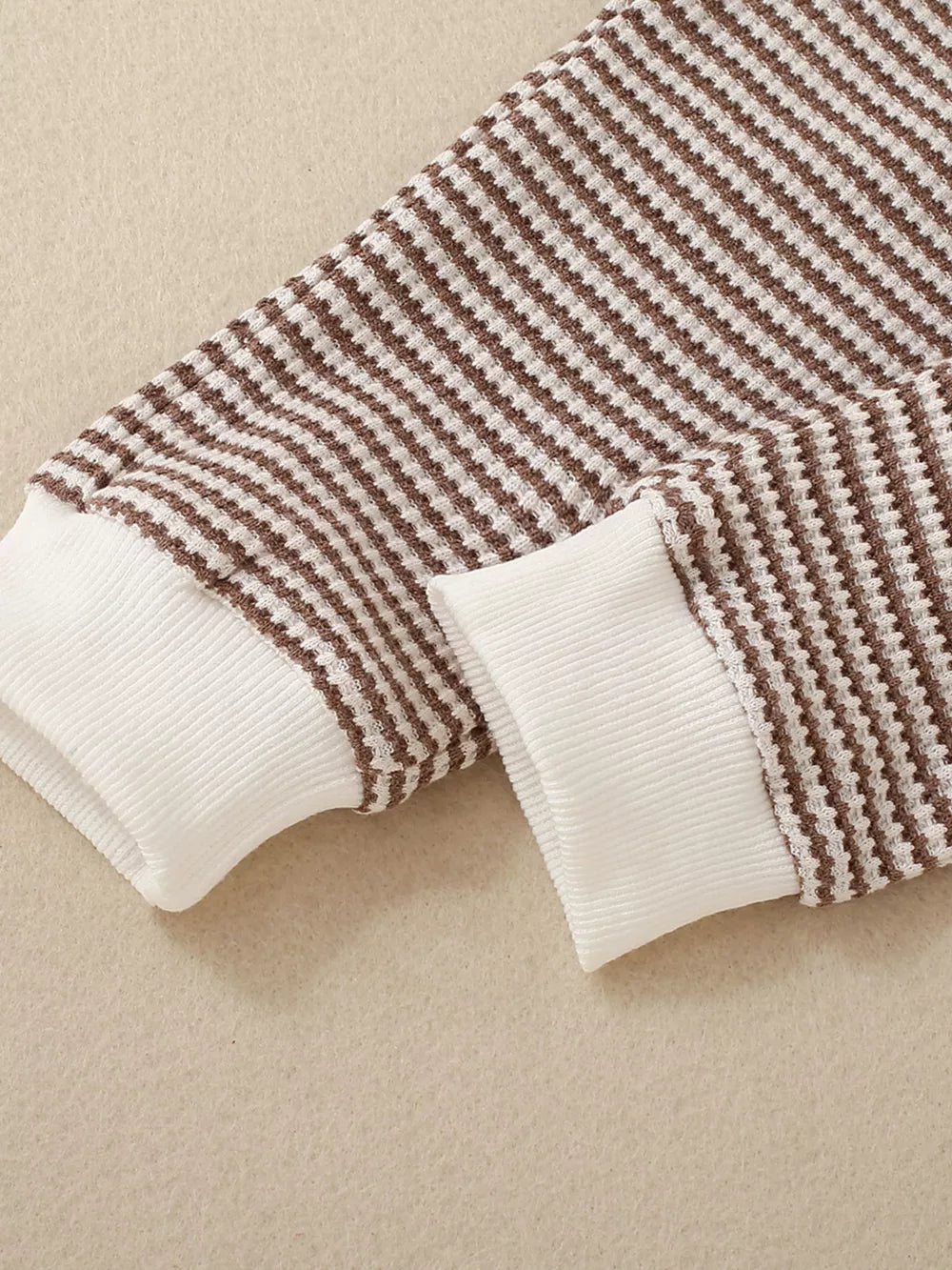 Baby knit set with brown and white stripes and white ribbed cuffs.