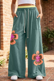 Teal cotton sweatpants with wide legs, floral appliques, and drawstring waist.
