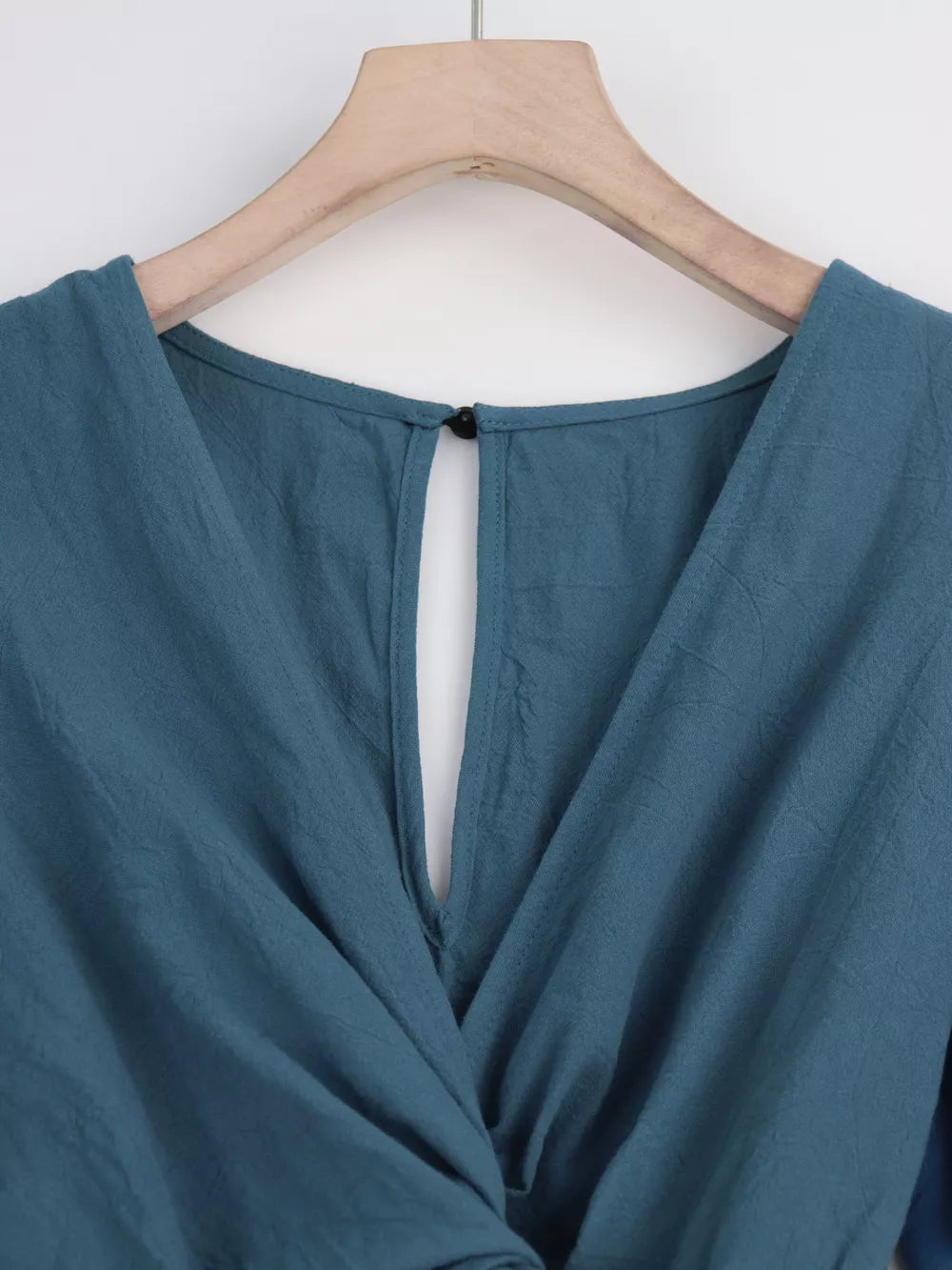 Haze Blue cotton romper with V-neck, button closure, and tie waist detail.