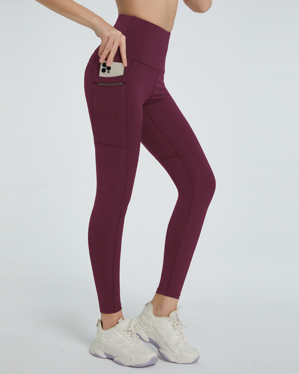 Burgundy pocketed leggings with a phone in the side pocket.