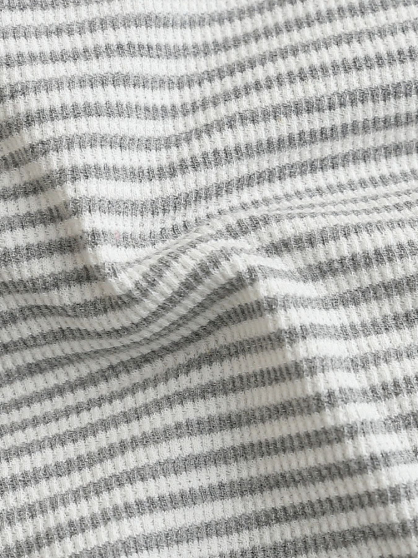 Baby one-piece with grey and white horizontal stripes in waffle knit fabric.