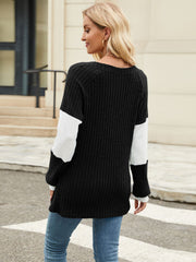 Ribbed knit henley sweater in black with white colorblock sleeves and a crew neck.