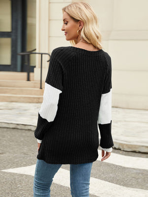 Ribbed knit henley sweater in black with white colorblock sleeves and a crew neck.