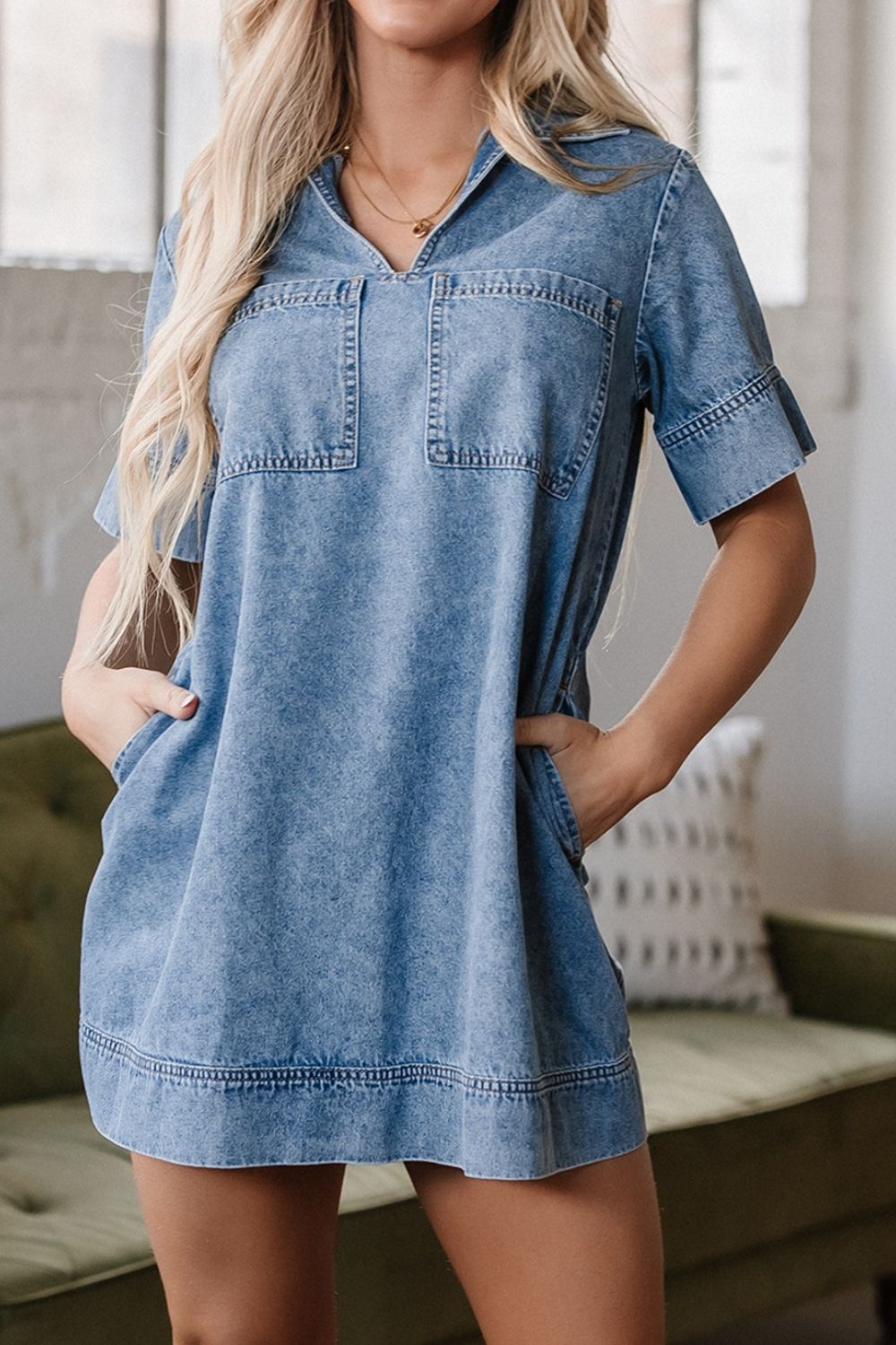 Light blue denim mini dress with short sleeves, a collared neckline, and two chest pockets.