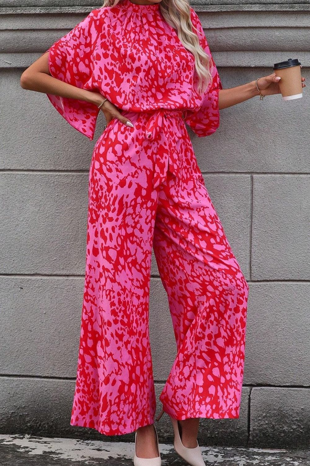 Crimson Splatter Tie-Waist Palazzo Jumpsuit in hot pink with wide legs and flutter sleeves.