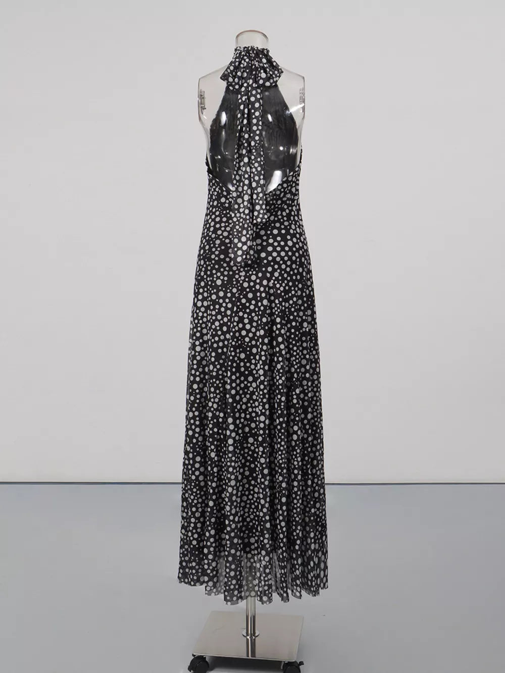 Black and white polka dot halter maxi dress with a flowing skirt and open back.