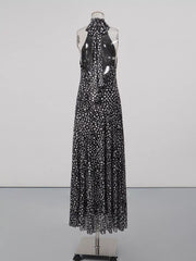 Black and white polka dot halter maxi dress with a flowing skirt and open back.