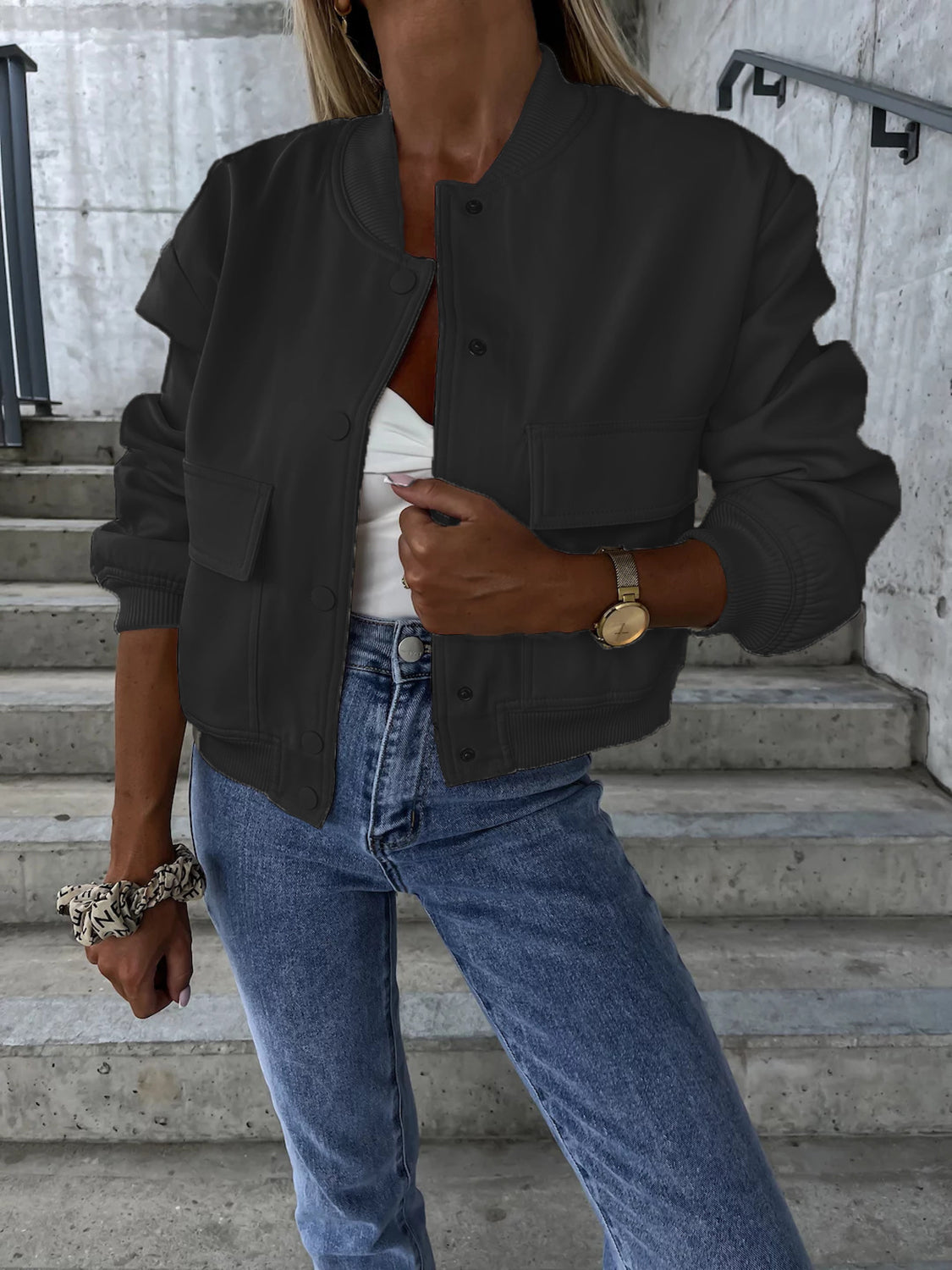 Black faux leather bomber jacket with sculpted sleeves and button front, styled with jeans.