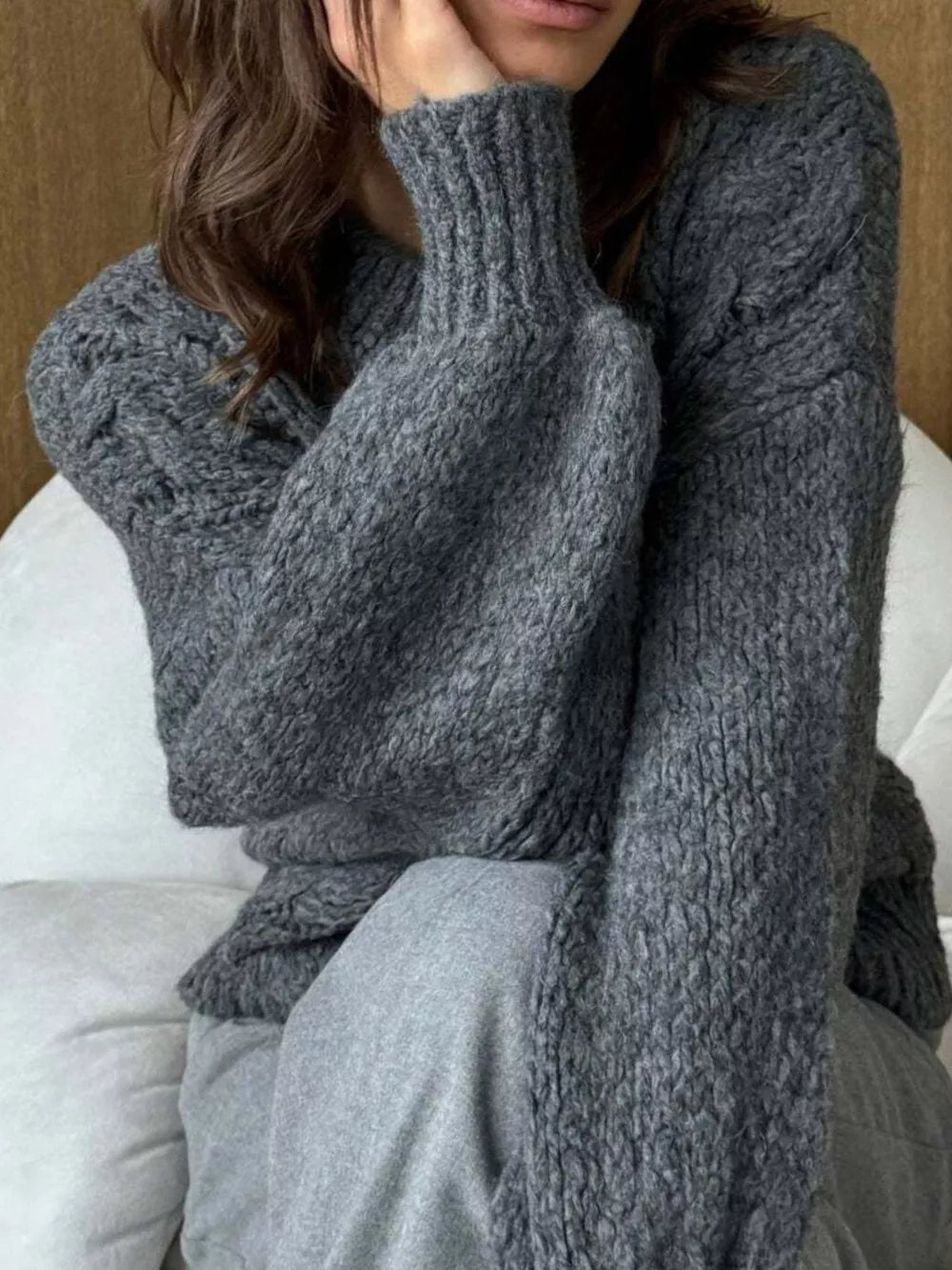 Gray cable-knit cardigan with textured sleeves and ribbed cuffs.