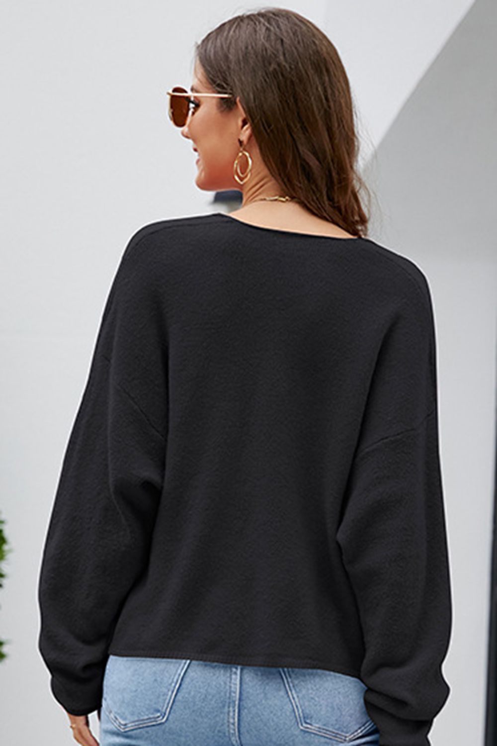 Black textured knit pullover sweater with a deep V-neck and long sleeves.