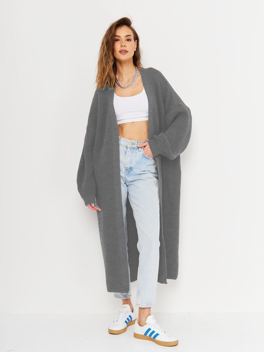 Oversized gray ribbed knit maxi cardigan with long sleeves and an open front, styled with a white crop top and jeans.
