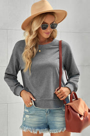 Gray sweatshirt with asymmetric raw hemline, crew neck, and long sleeves.