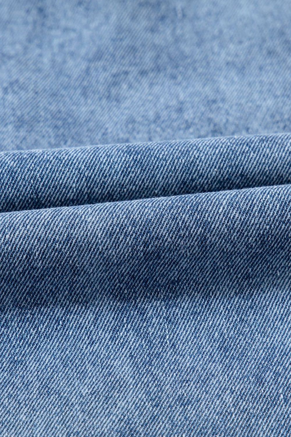 Utility denim mini dress in light blue, showing fabric texture and fold detail.