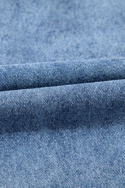 Utility denim mini dress in light blue, showing fabric texture and fold detail.