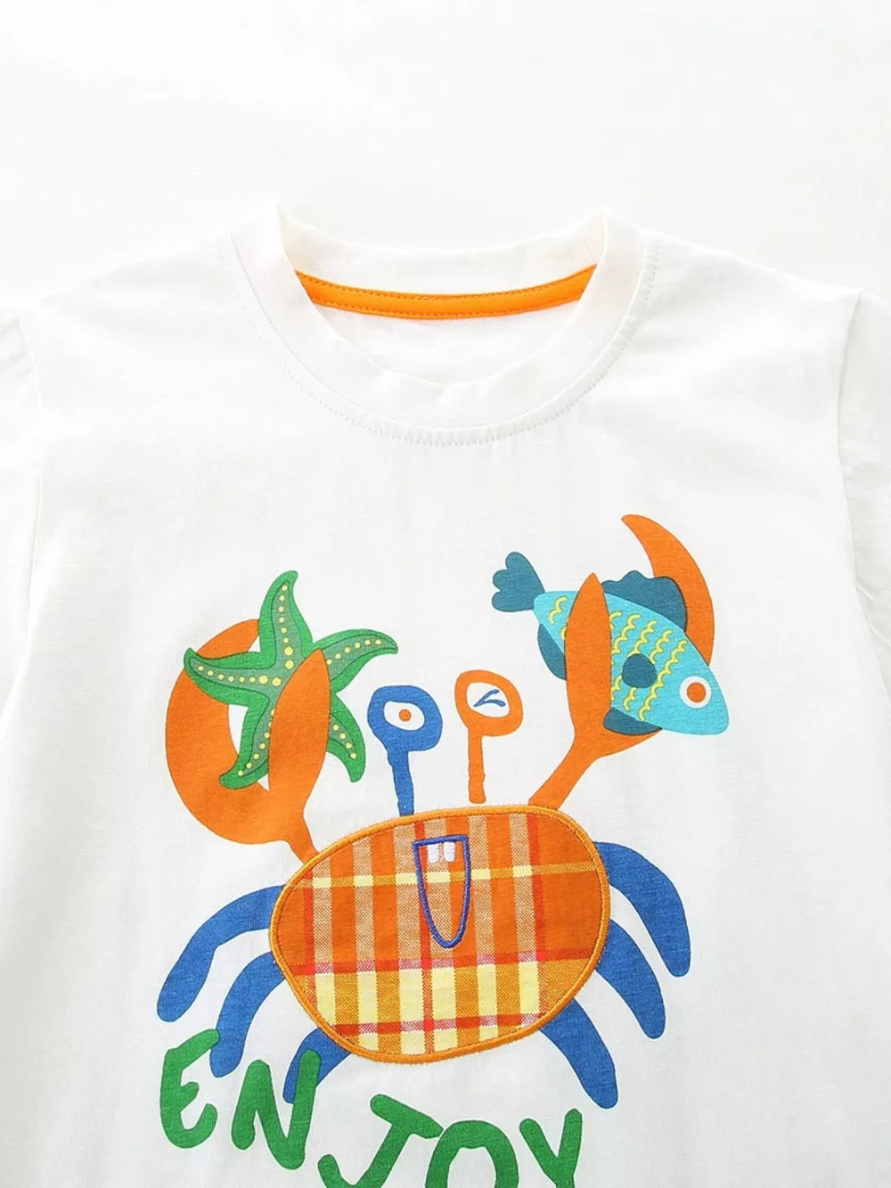 White cotton toddler t-shirt with playful crab graphic and orange trim.