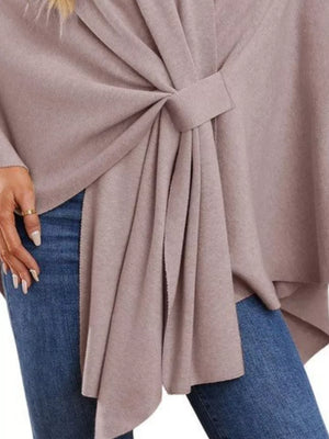 Knit cape top in tan with tie-front detail and draped elegance, styled with jeans.