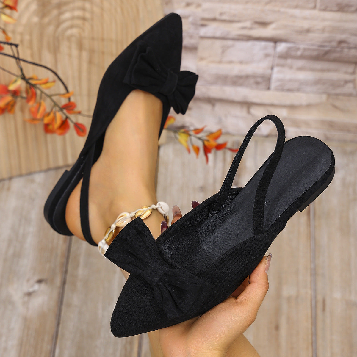 Black bow accent slingback slip-ons with pointed toe and elastic ankle strap.
