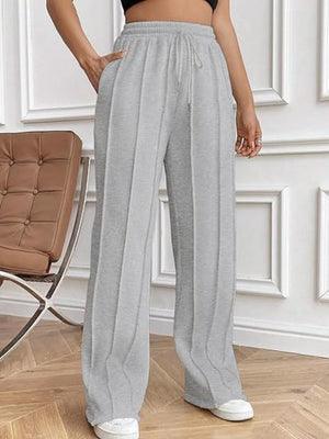 Gray pleated wide-leg lounge trousers with drawstring waist and pockets.