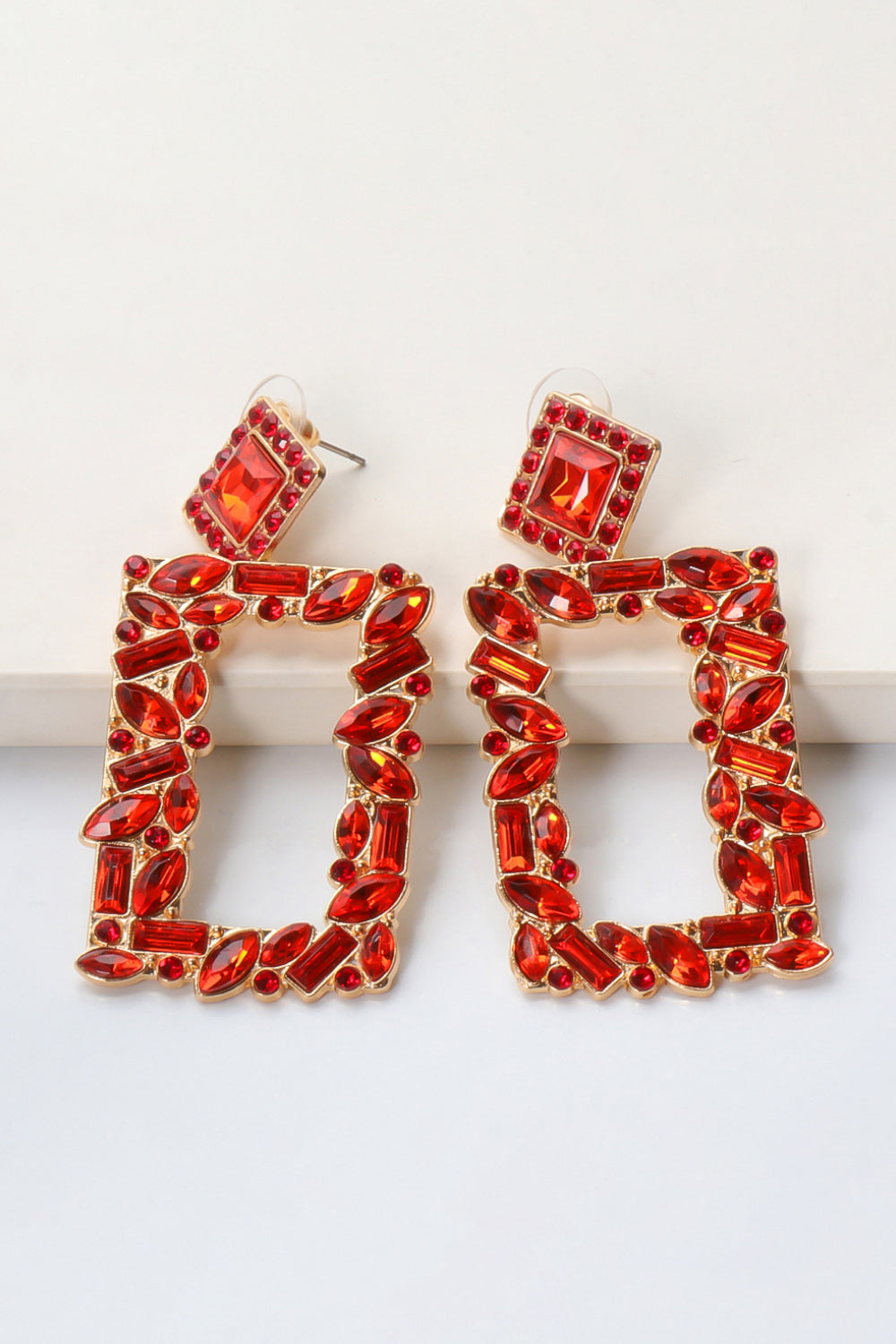 Red geometric jewel box earrings with gold alloy setting and faceted red stones.