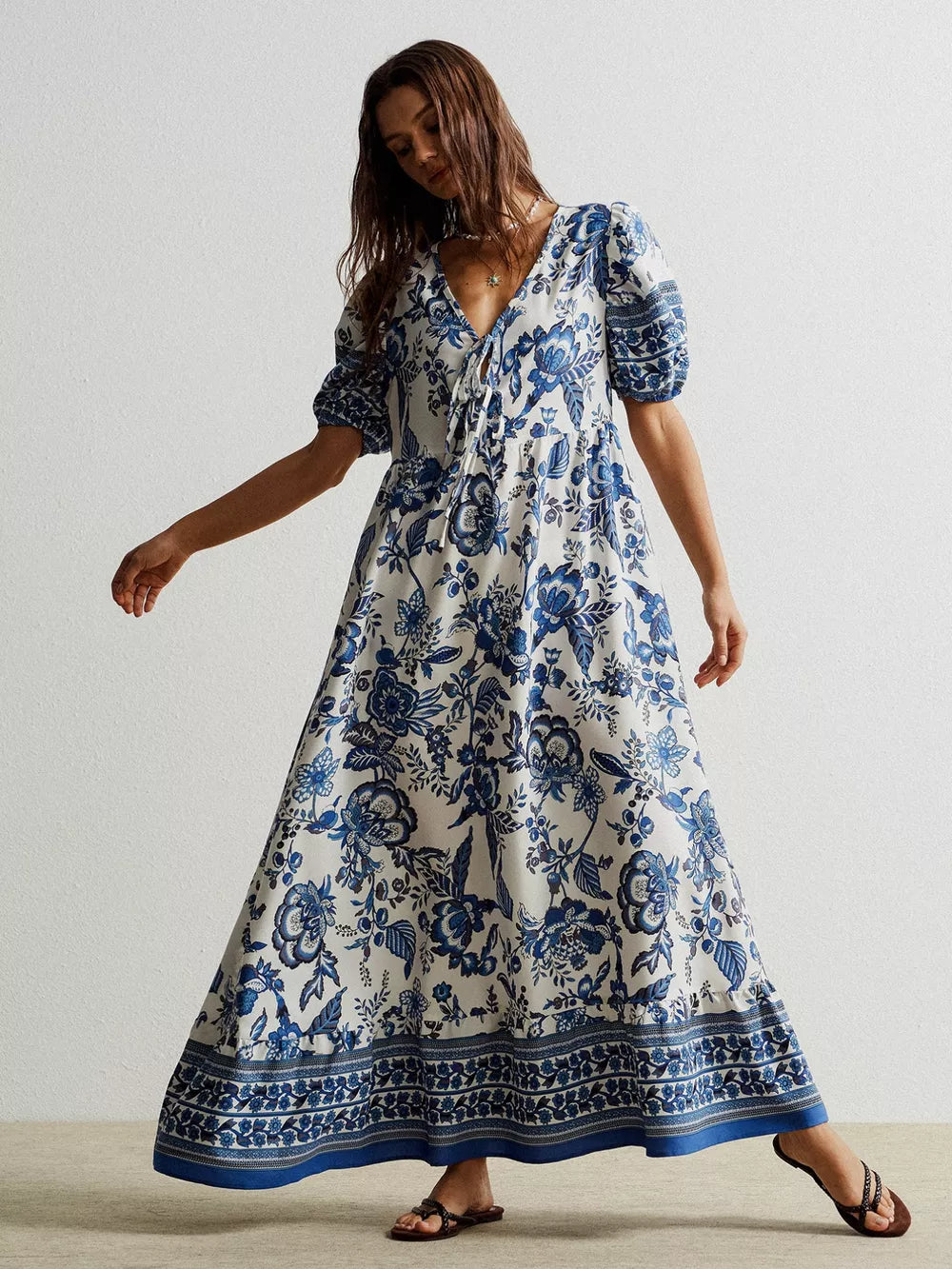 Charming floral maxi dress with tie-neck, puff sleeves, and blue floral print on white.