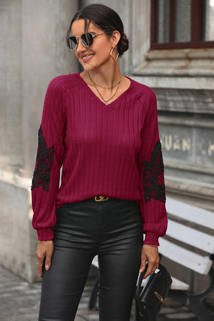 Deep red ribbed knit sweater with black lace appliqué on sleeves and V-neck.
