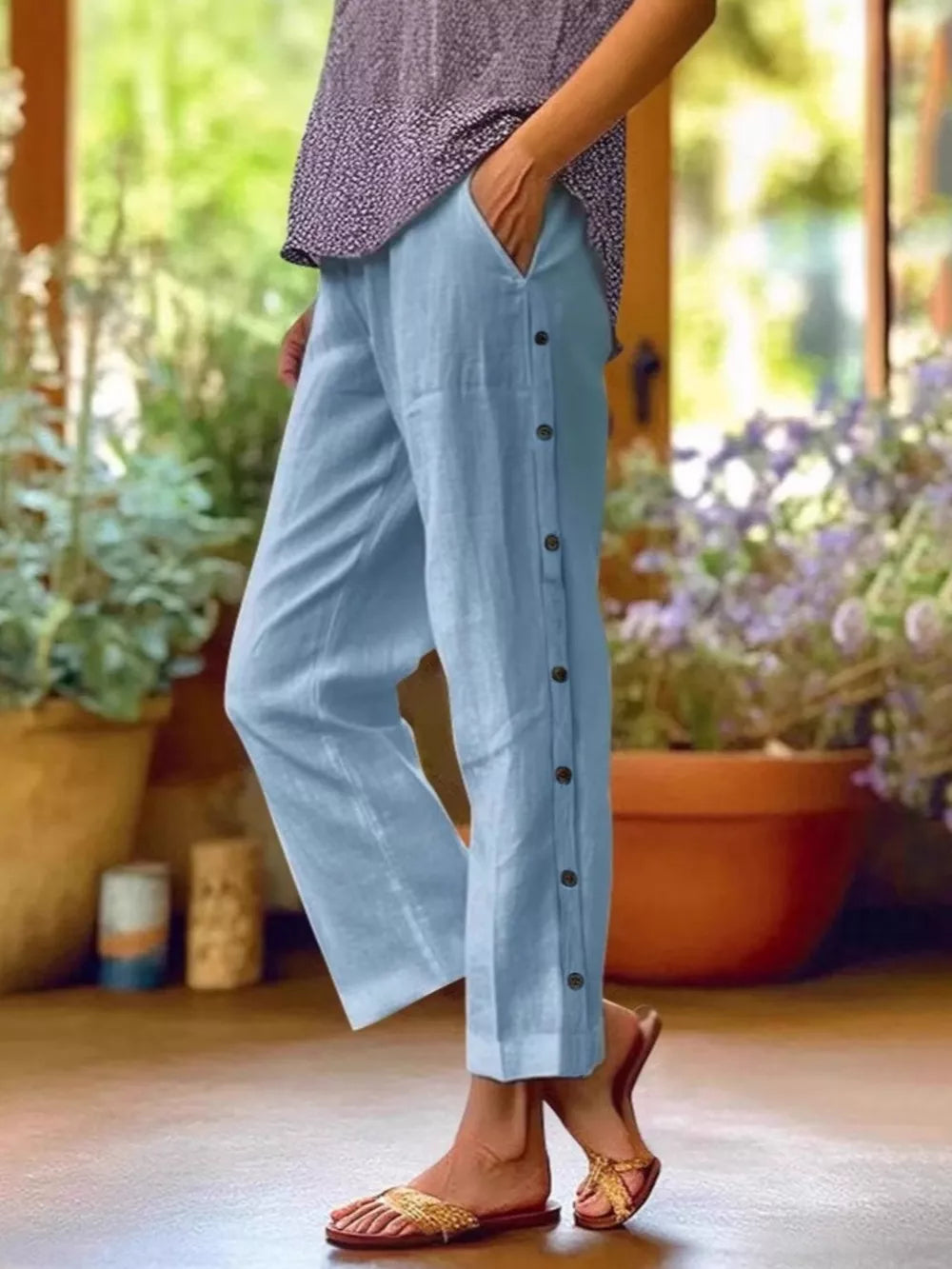 Sky blue relaxed fit pants with decorative buttons down the side and pockets.