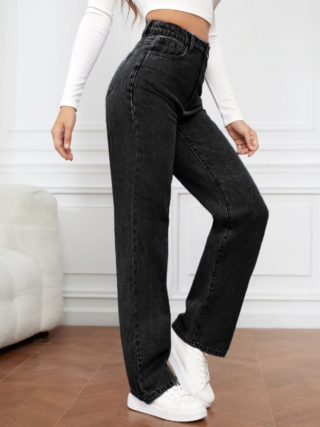 Black wide-leg denim jeans with a sculpted high rise, styled with white sneakers.