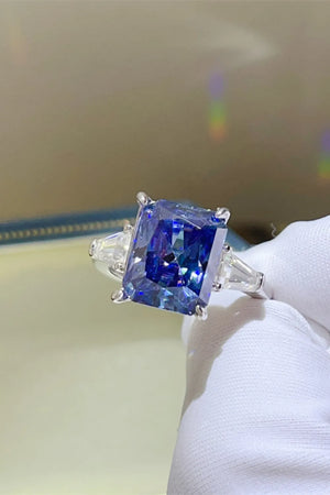 Radiant cut royal blue sapphire and moissanite ring with three stones.