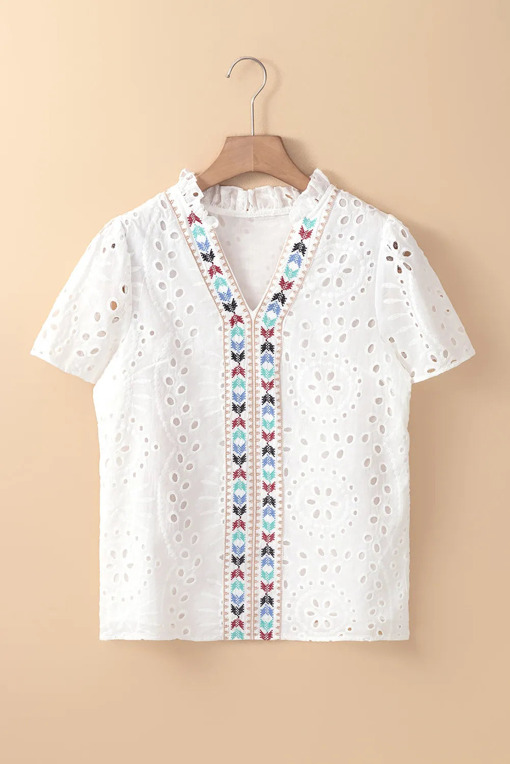 White eyelet V-neck blouse with colorful embroidered trim and ruffled collar.