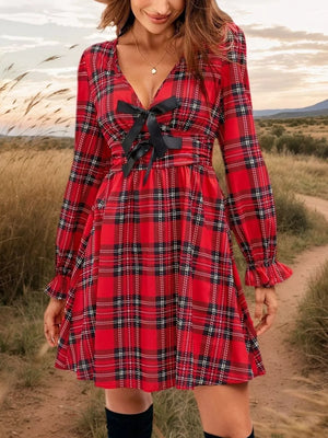 Red plaid mini dress with deep V-neck and black bow detail, long sleeves with ruffled cuffs.