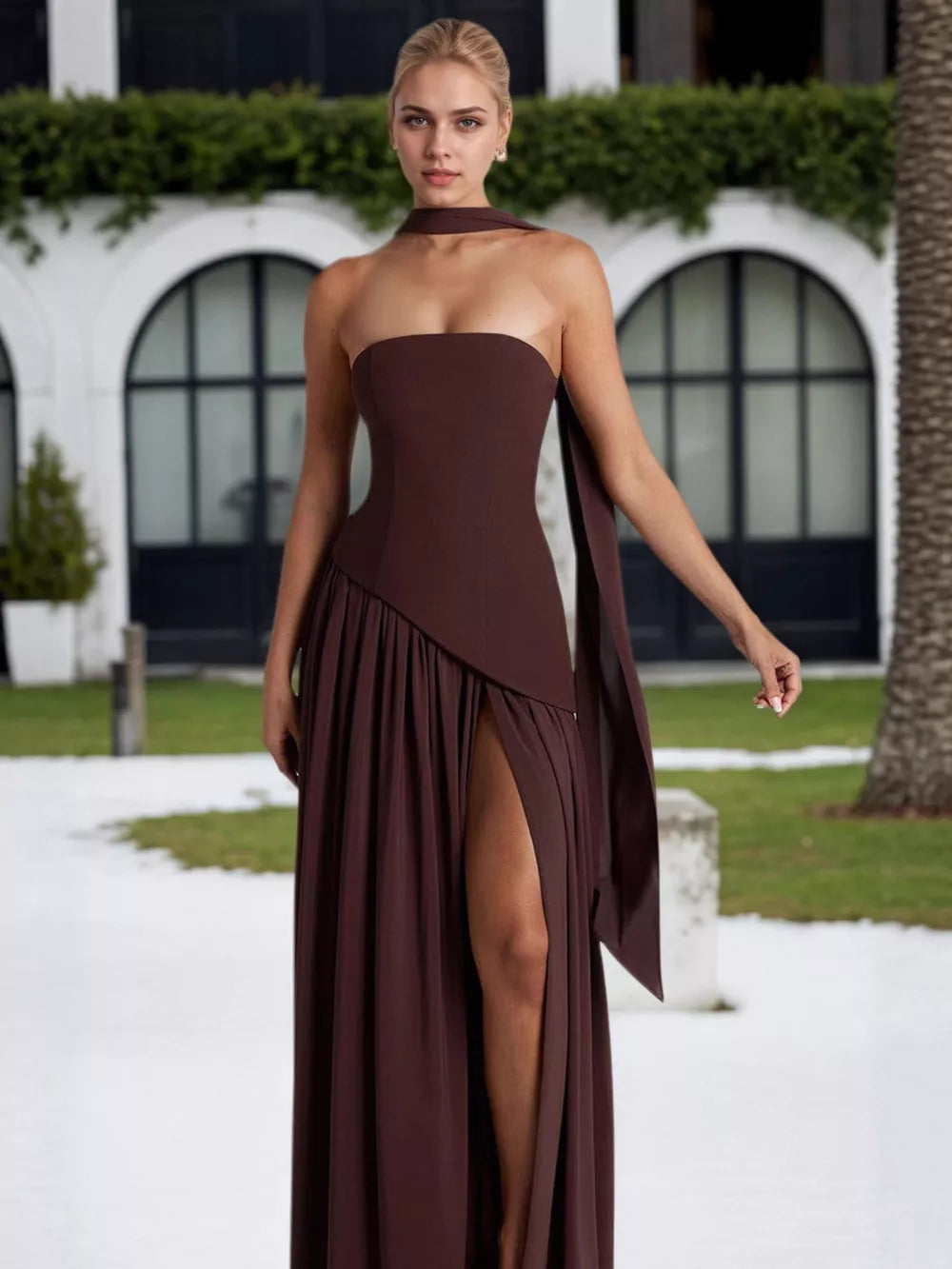 Brown asymmetrical maxi dress with slit and scarf detail.