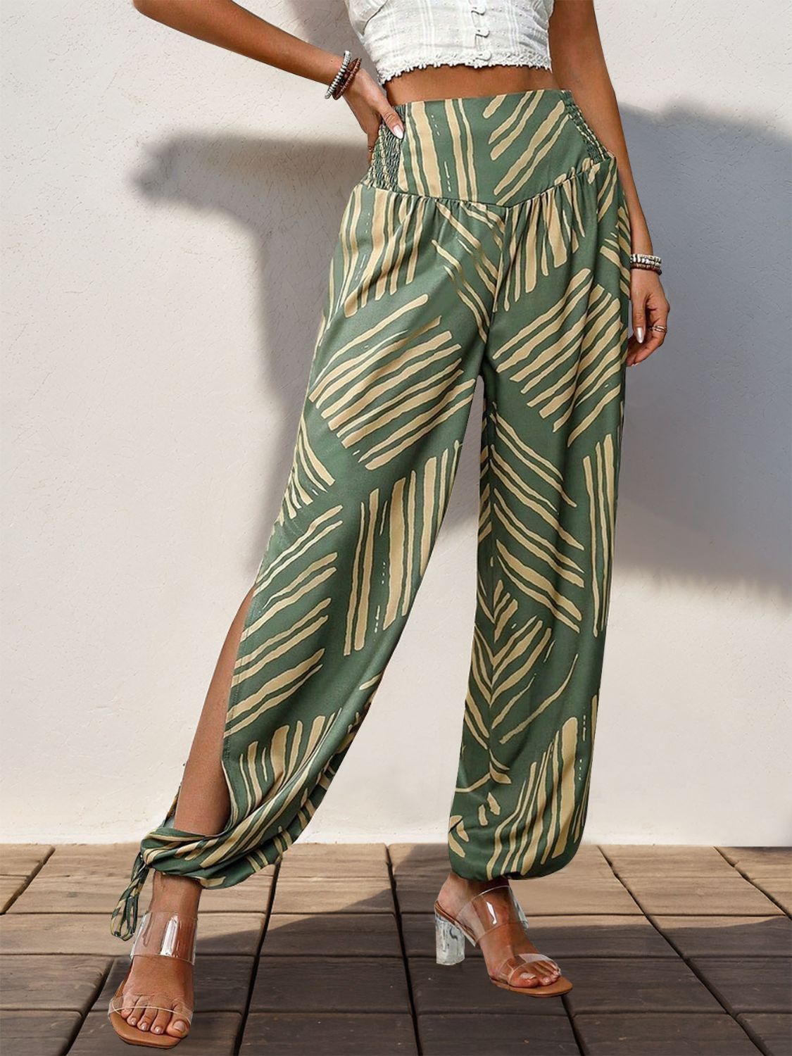 Moss green palazzo trousers with abstract print, smocked waist, and high slit legs.