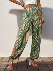 Moss green palazzo trousers with abstract print, smocked waist, and high slit legs.