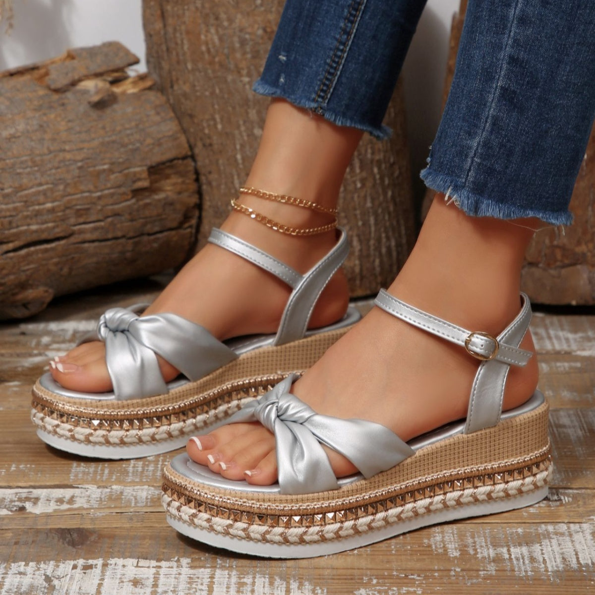 Silver bow knot wedge sandals with ankle buckle and braided trim.