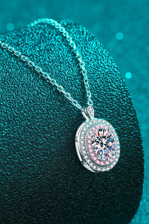 Silver halo moissanite pendant necklace with a round brilliant cut center stone and pink accent stones.