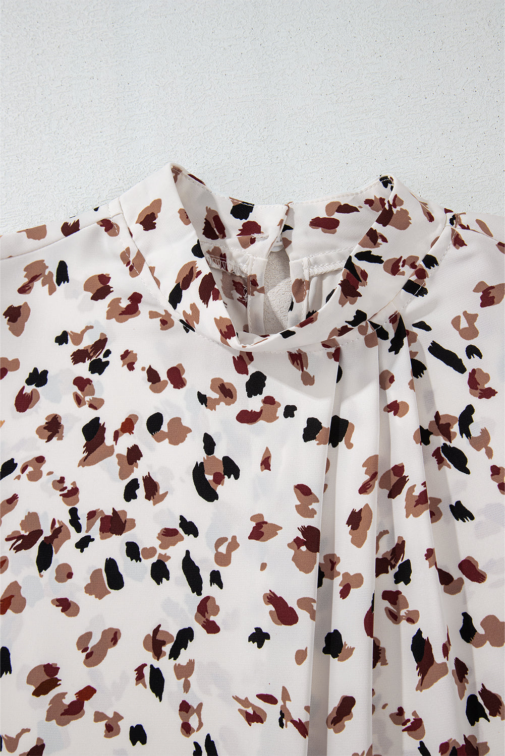 White high-neck blouse with abstract print and pleat detail