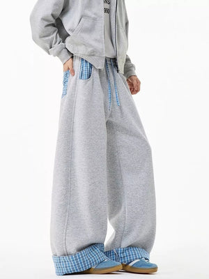 Gray wide-leg sweatpants with drawstring and blue plaid pocket details.