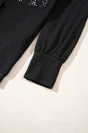 Black textured knit shirt jacket with sequin pocket detail and ribbed cuffs.