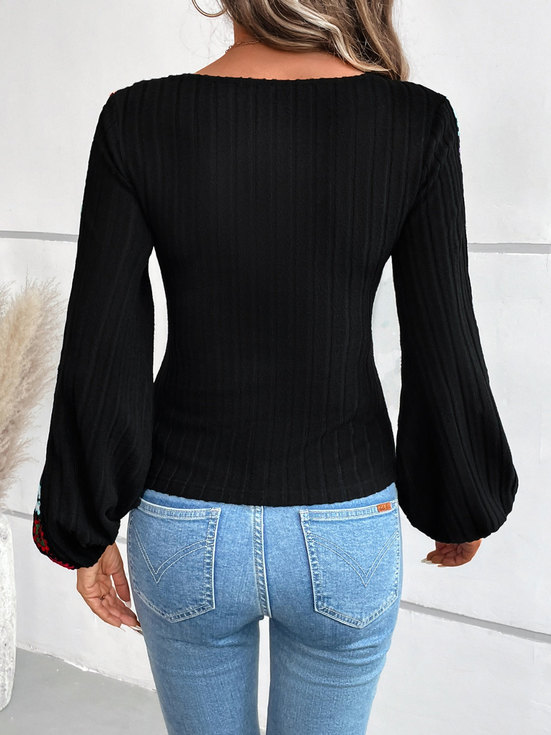 Black ribbed knit blouse with embroidered balloon sleeves.