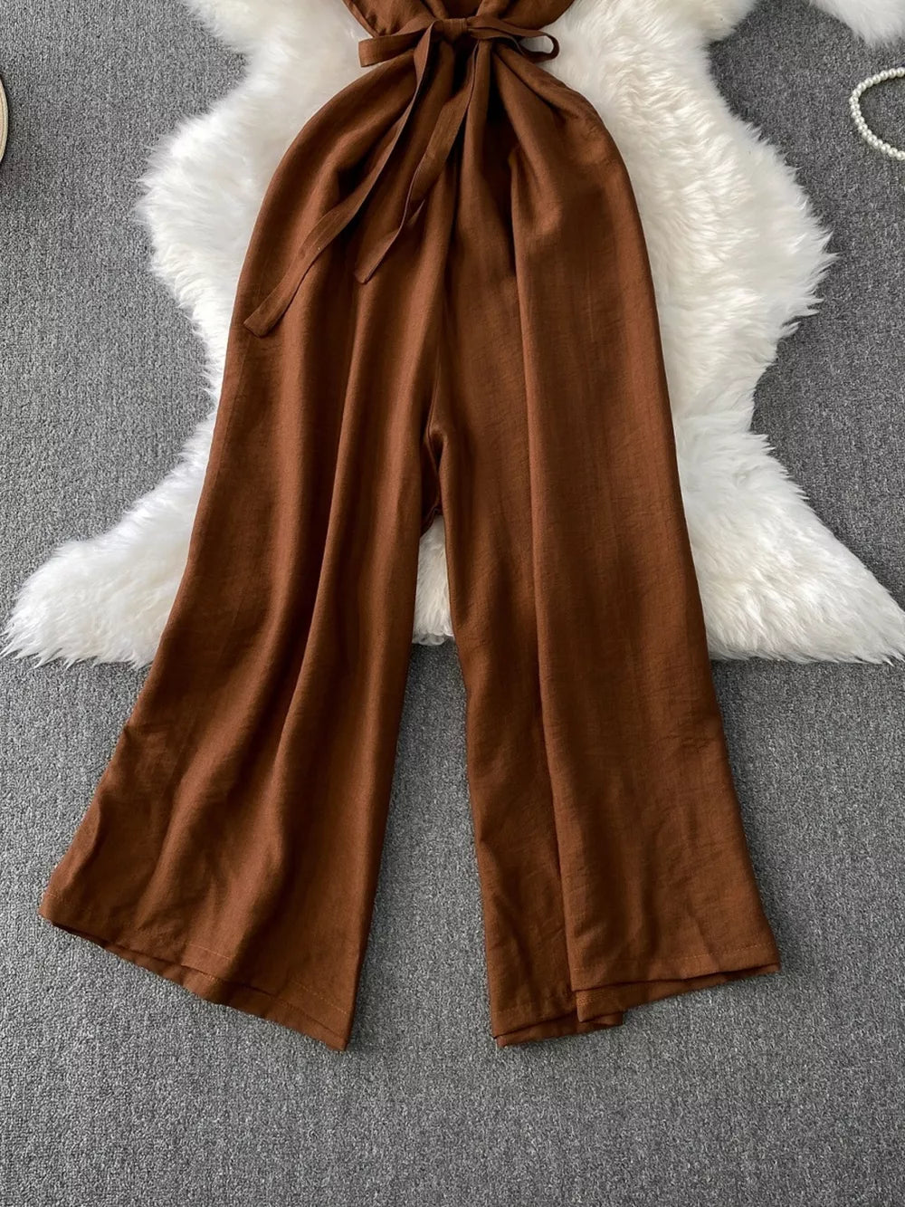 Brown V-neck wide leg jumpsuit with tie waist and button details