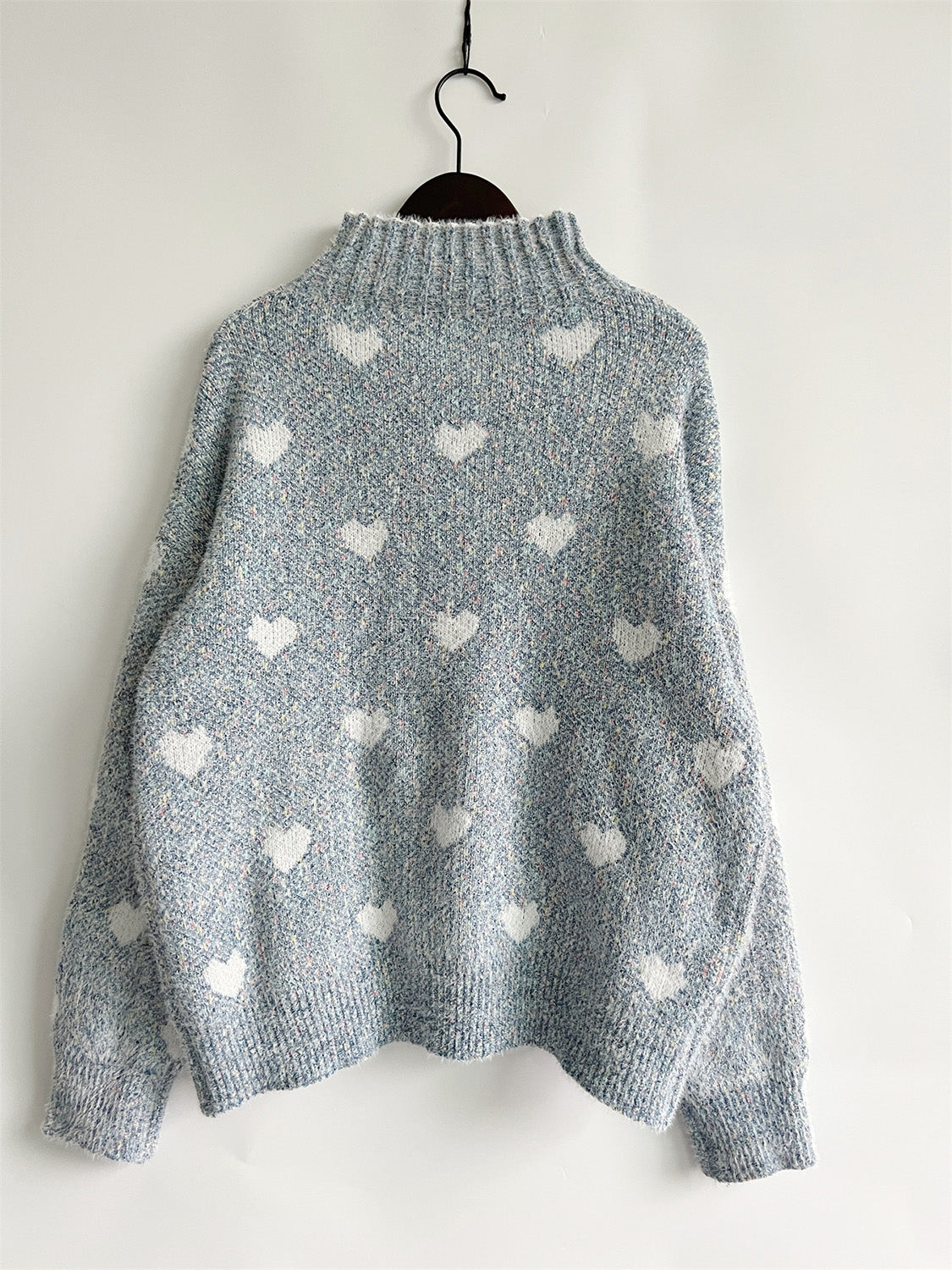 Mint blue acrylic turtleneck sweater with allover white heart motif and textured knit.