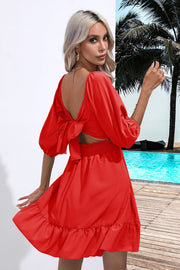 Red mini dress with open back, bow-tie sleeves, smocked waist, and ruffled hem.