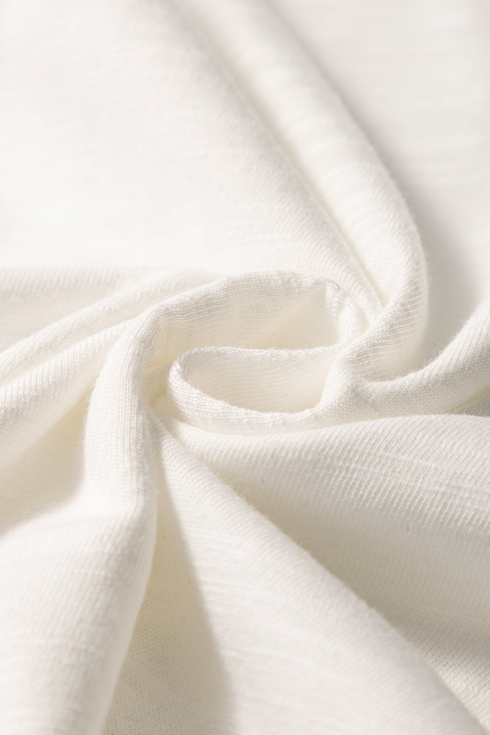 White embroidered tee with flutter sleeves, showing fabric texture.