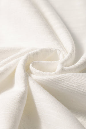 White embroidered tee with flutter sleeves, showing fabric texture.