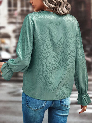Turquoise satin blouse with subtle animal print and ruffle cuffs.